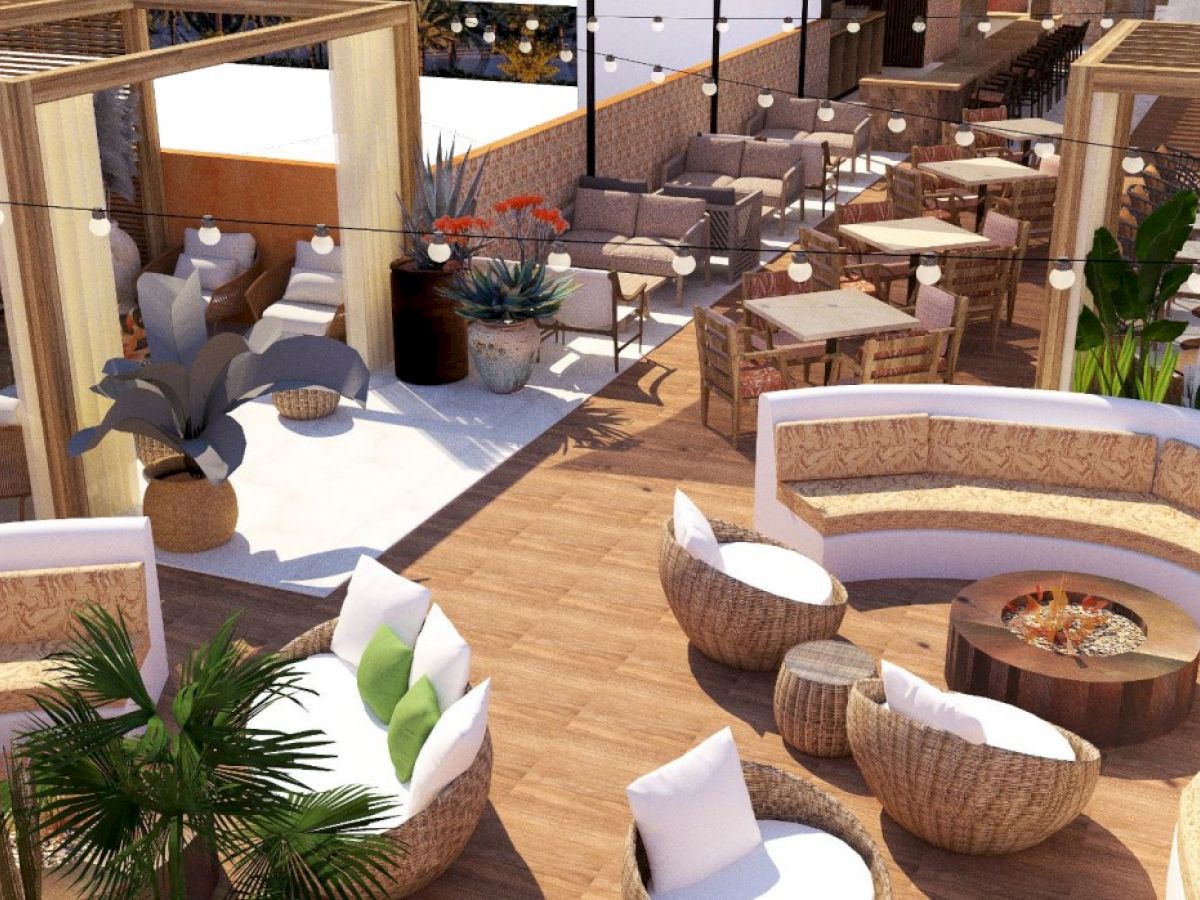 This image depicts a stylish outdoor lounge area with modern furniture, plants, and a fire pit, designed for a comfortable and social atmosphere.