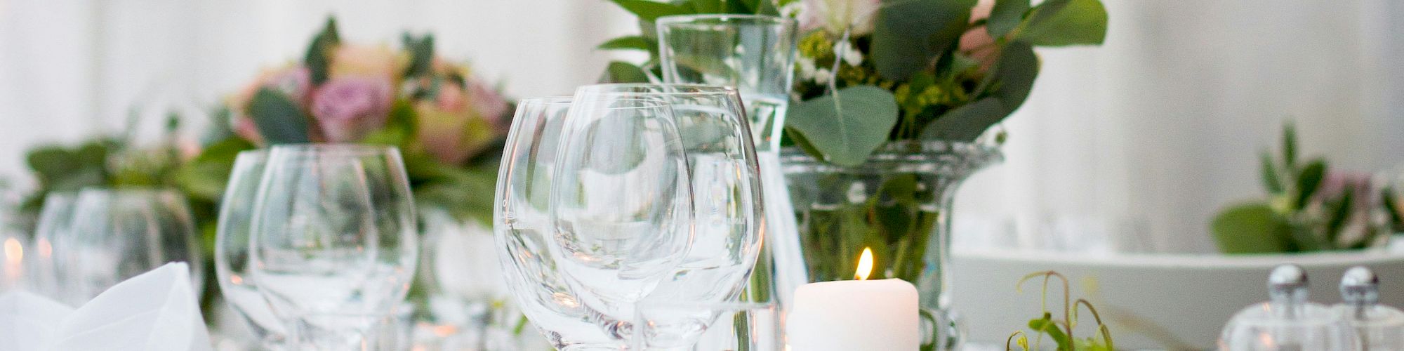 A table elegantly set with wine glasses, candles, and floral centerpieces, creating a sophisticated and inviting atmosphere for dining.